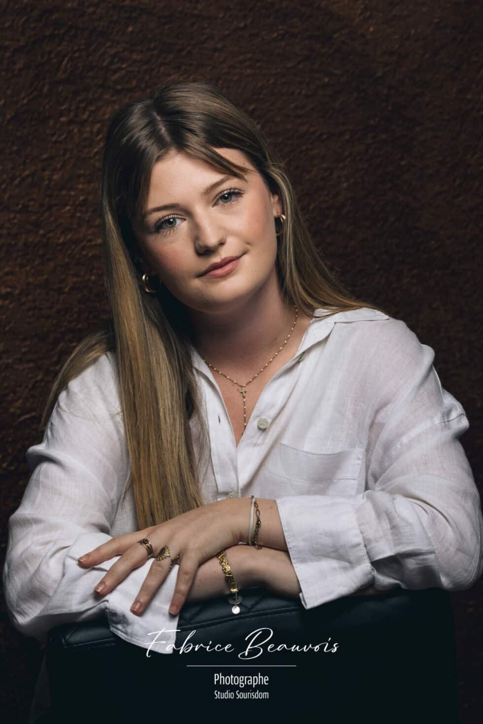 Portrait studio de face bras croisés sur un siège